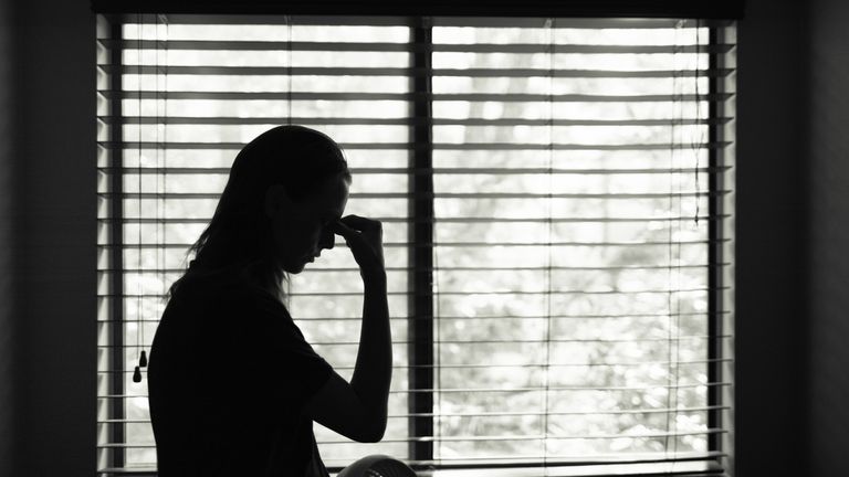silhouette of woman by a window touching her face between the eyes