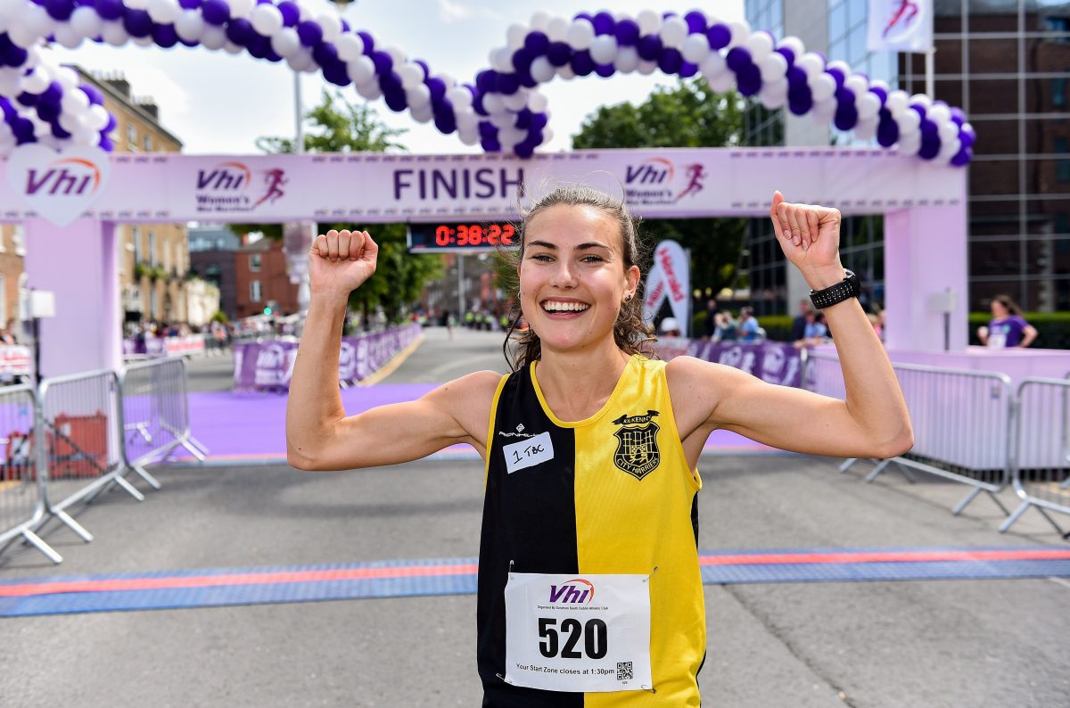 woman raising her hands at the finish line