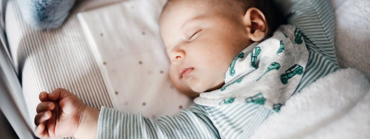 A baby lays sleeping in crib