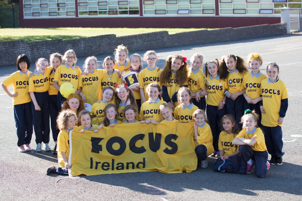 A group of school children wearing Focus Ireland t-shirts. They posing for the photo.