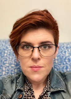 Selfie of woman with short red hair and glasses.