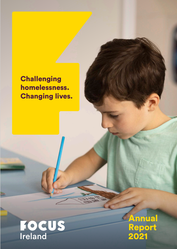 Focus Ireland 2021 Annual Report front page. A little boy sits at a desk colouring a drawing of a house. He is wearing a light green t-shirt.