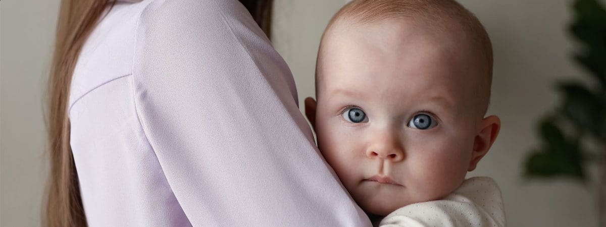 Mother holding baby with blue eyes.