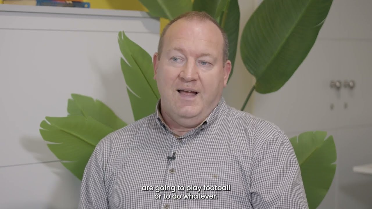 A man has his mouth open as he speaks. He is gazing towards the left. The subtitles reading 