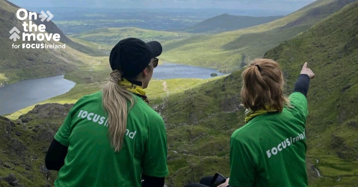 Two Focus Ireland Hikers point towards a view looking down from Carrauntoohil.