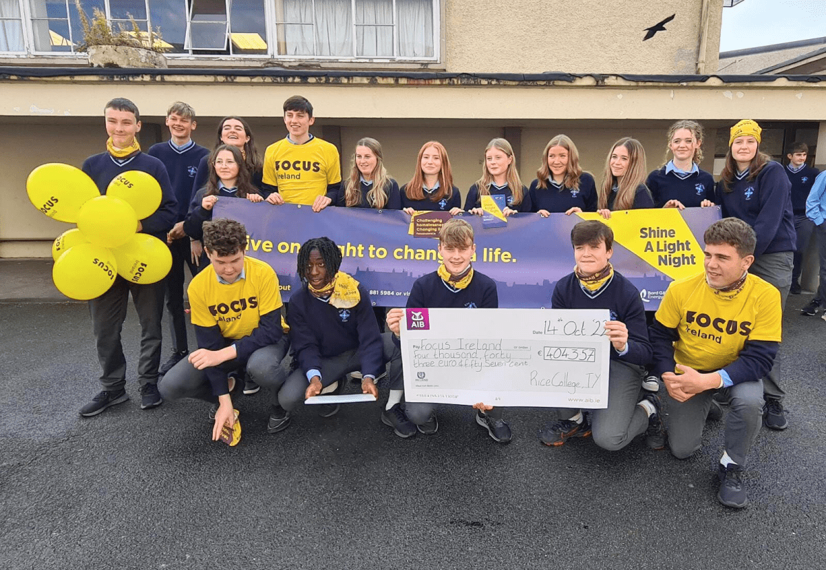 Students who took part in Shine A Light stand with a cheque that they presented to Focus Ireland. They are wearing yellow Focus Ireland t shirts.