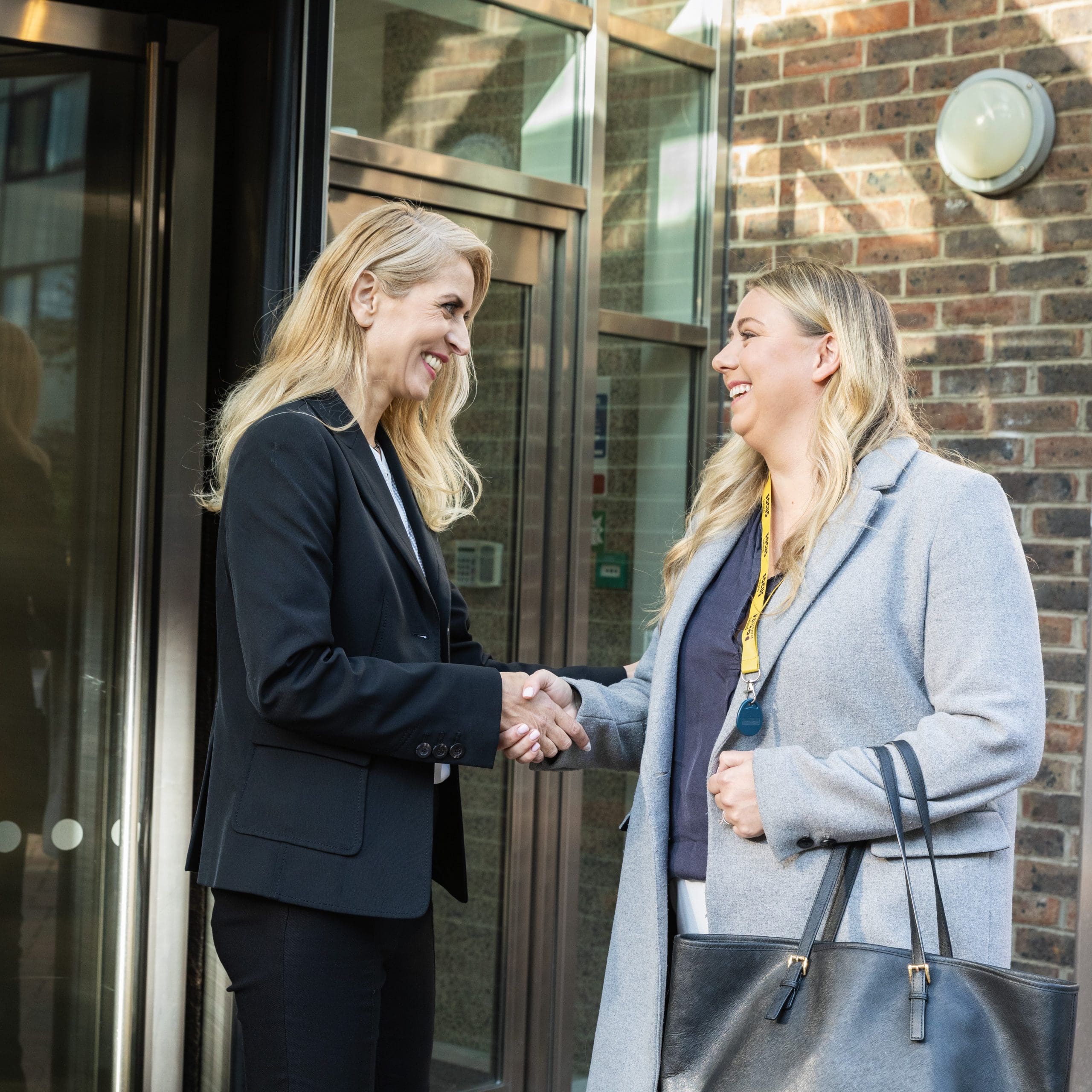 A Focus Ireland employee shakes hands with a donor outside their office building.