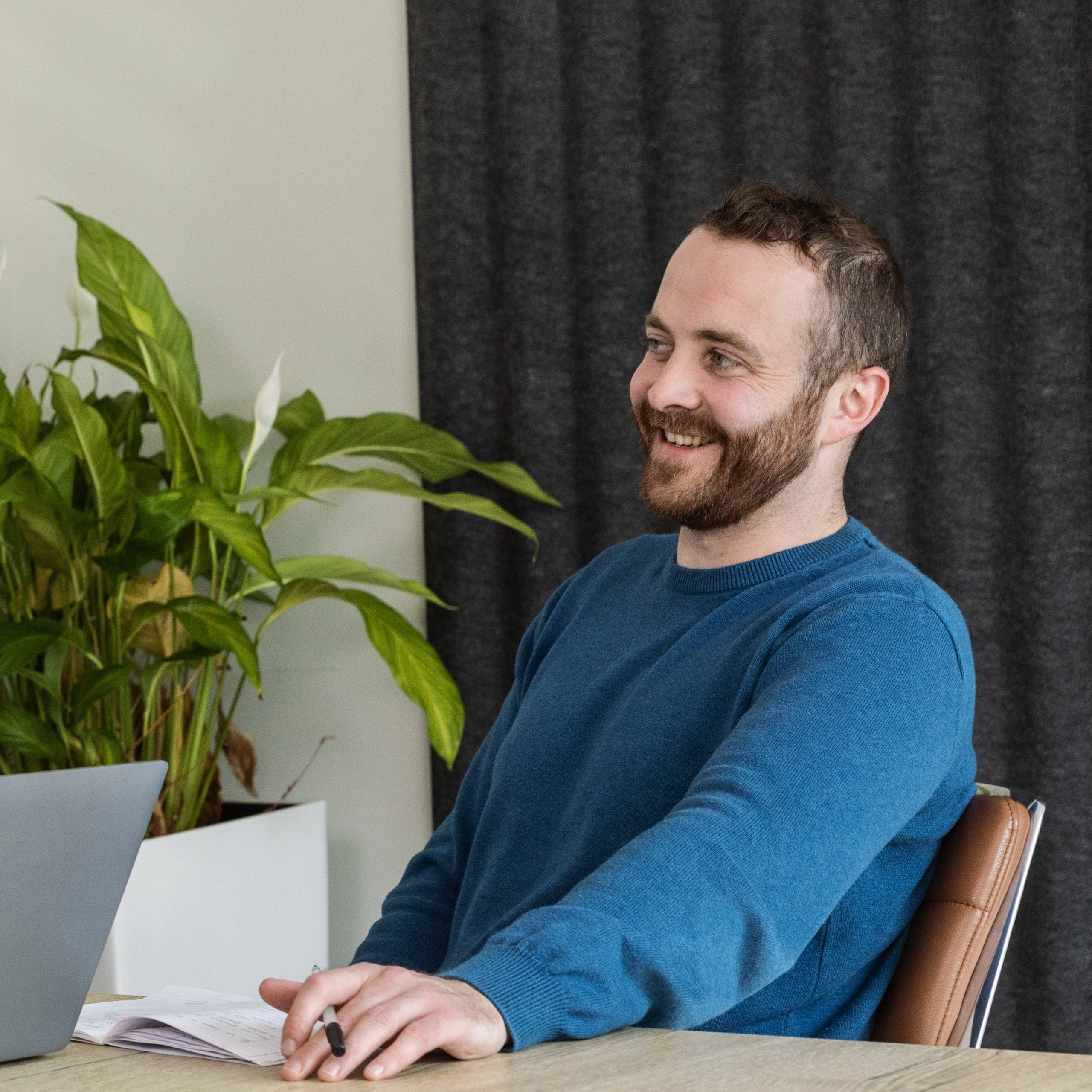 A Focus Ireland employee sits at a meeting table. He is smiling to someone out of shot.