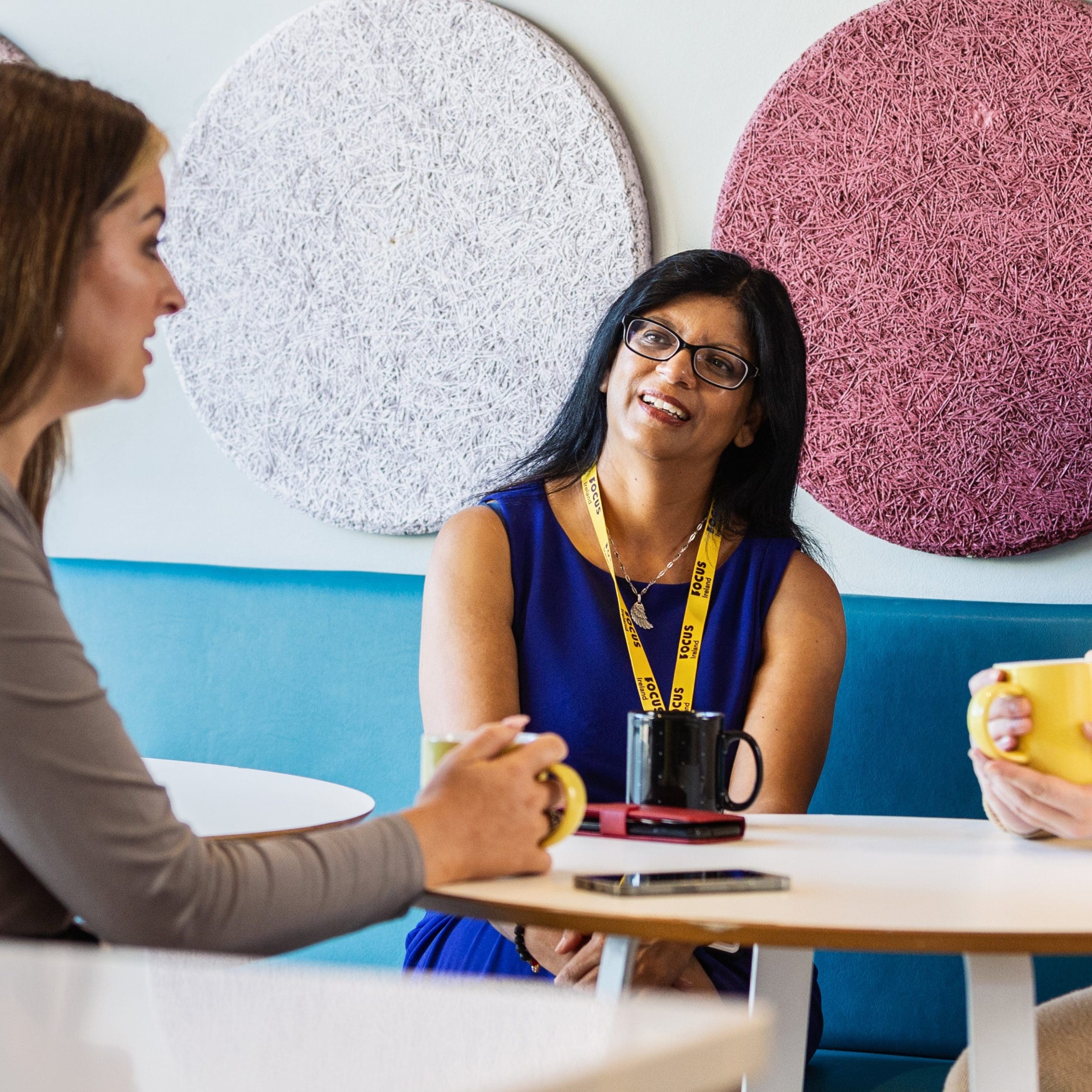 Focus Ireland employees sit around a coffee table in the office kitchen.