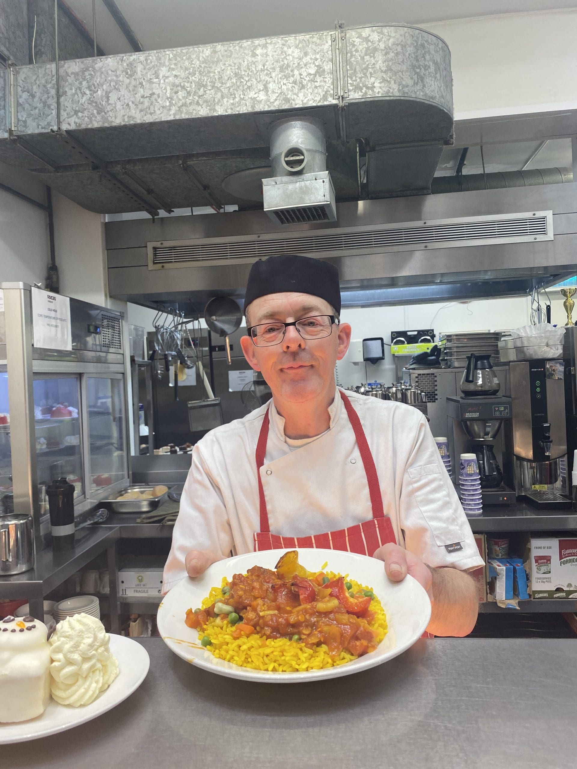 A chef holds out a plate of food.