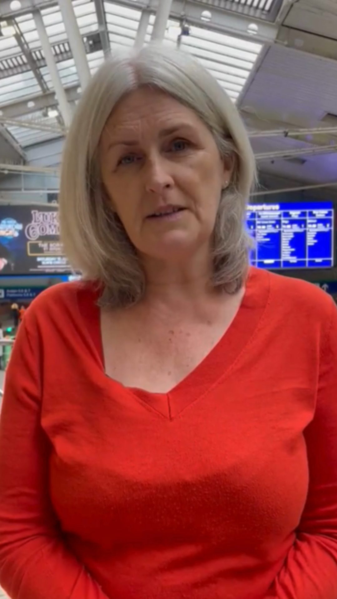 Joanne Bissett speaks to camera. They are wearing a red top.