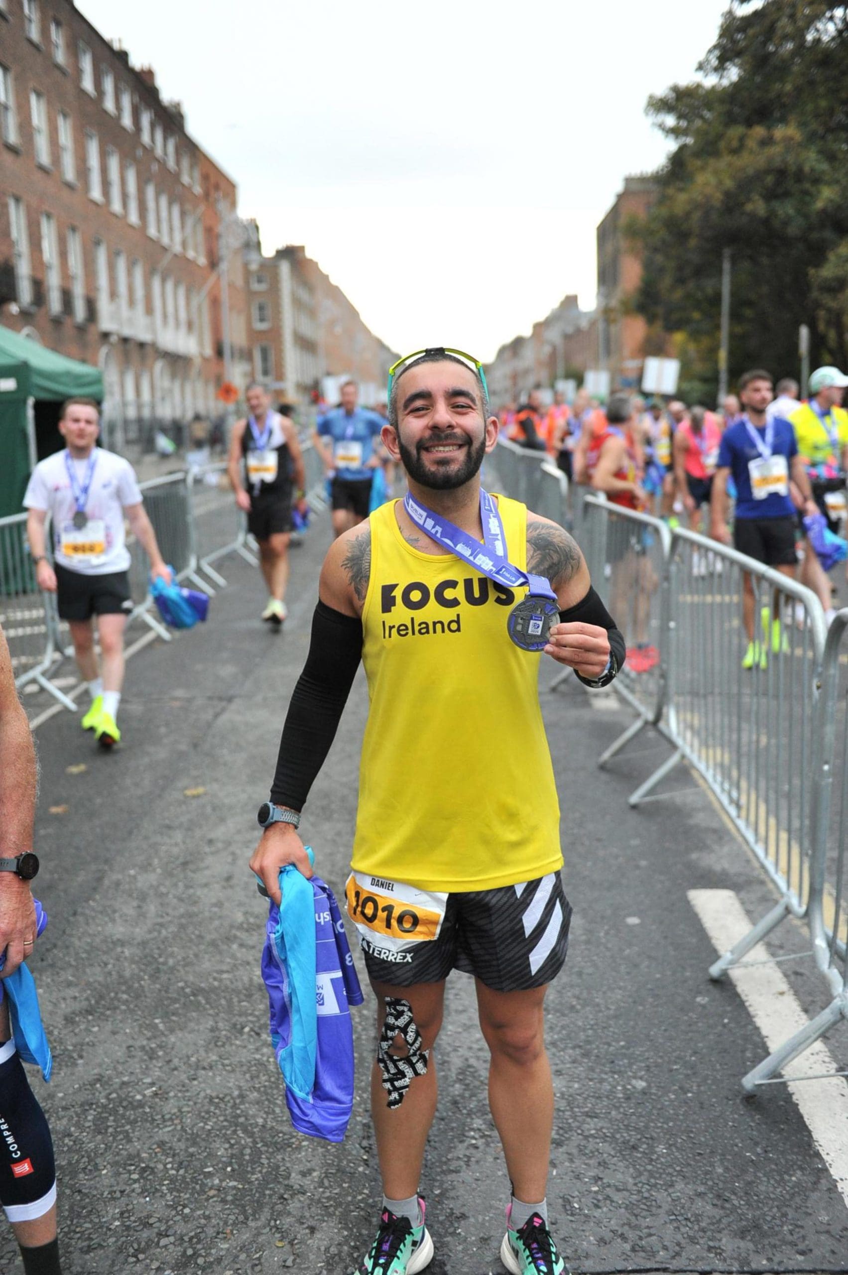 A runner wears a Focus Ireland top as they hold their marathon finisher medal.
