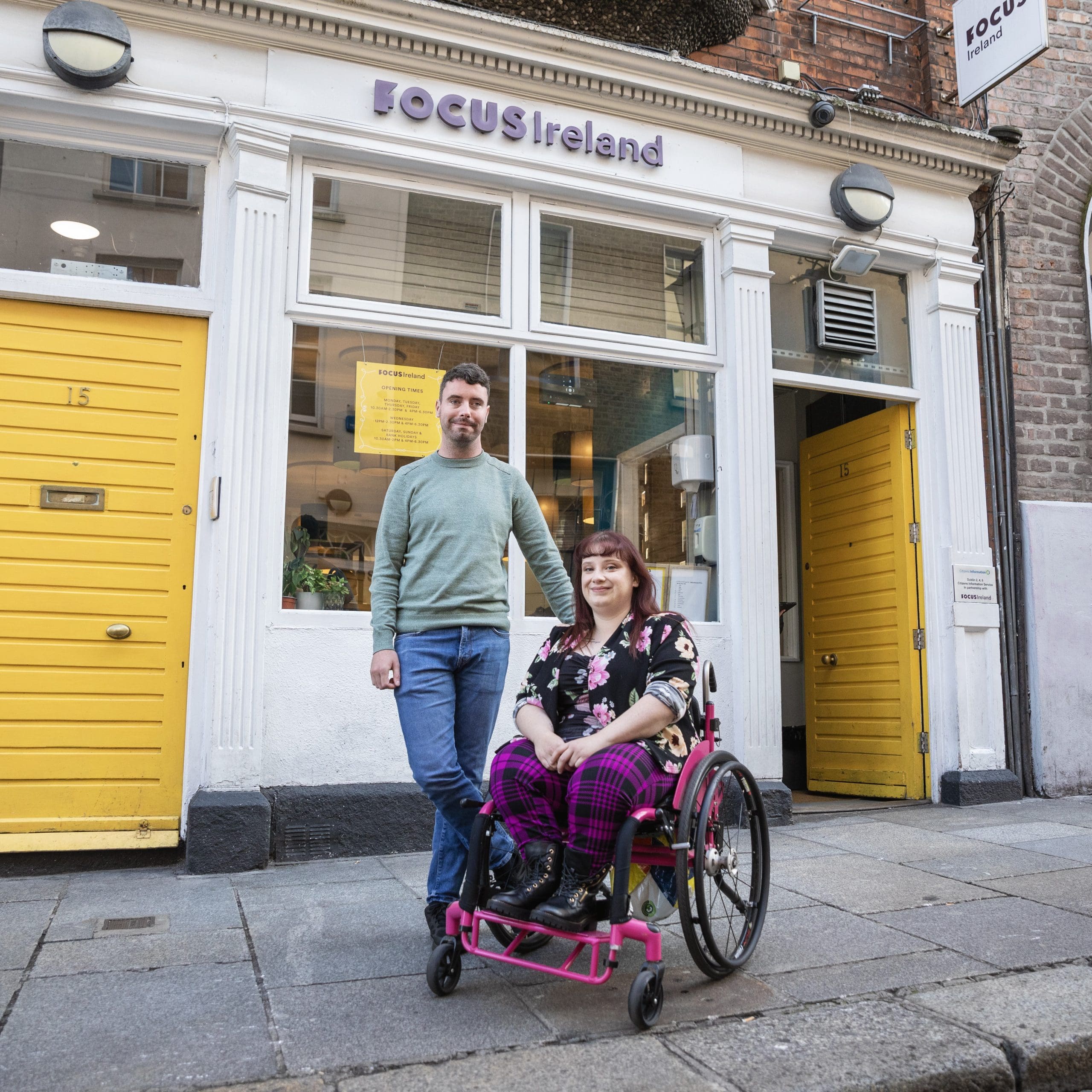A man and woman outside the Focus Ireland Coffee Shop. The woman is a wheelchair user.